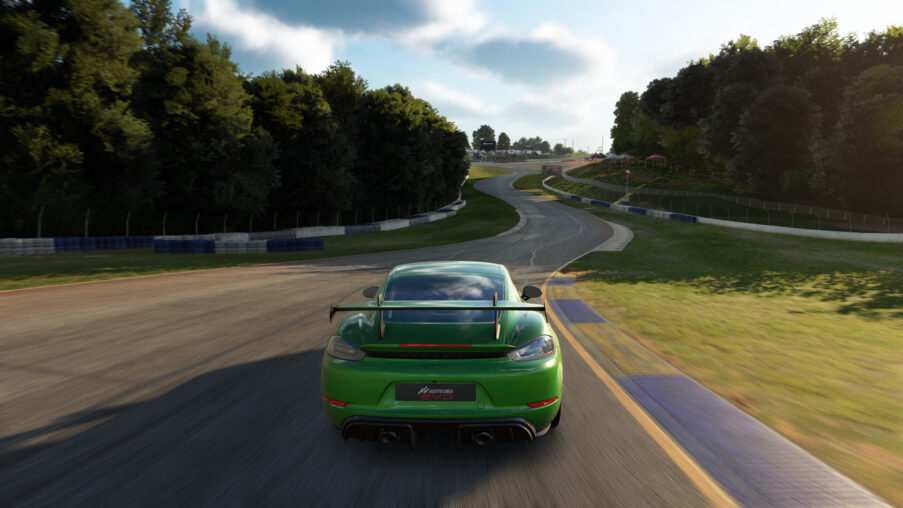 Driver's cockpit view of a GT race car cornering on a race track at dusk, hands gripping the steering wheel
